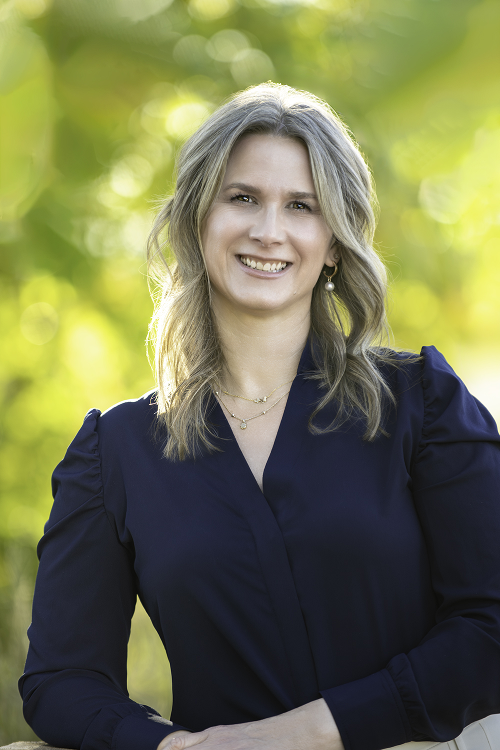 Headshot of Lori Pereira smiling with green blurred background.